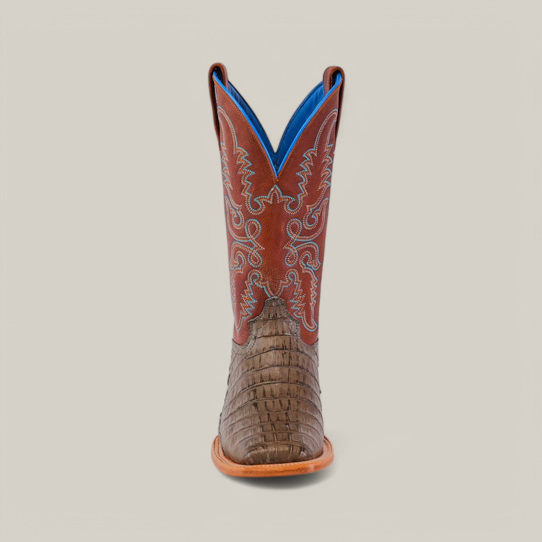 The Exotic Caiman Belly Tail - Gray - Square Toe features a brown, textured exotic leather lower with a red shaft adorned with intricate white stitching. Its blue-lined interior embodies Western style against a simple, light background.