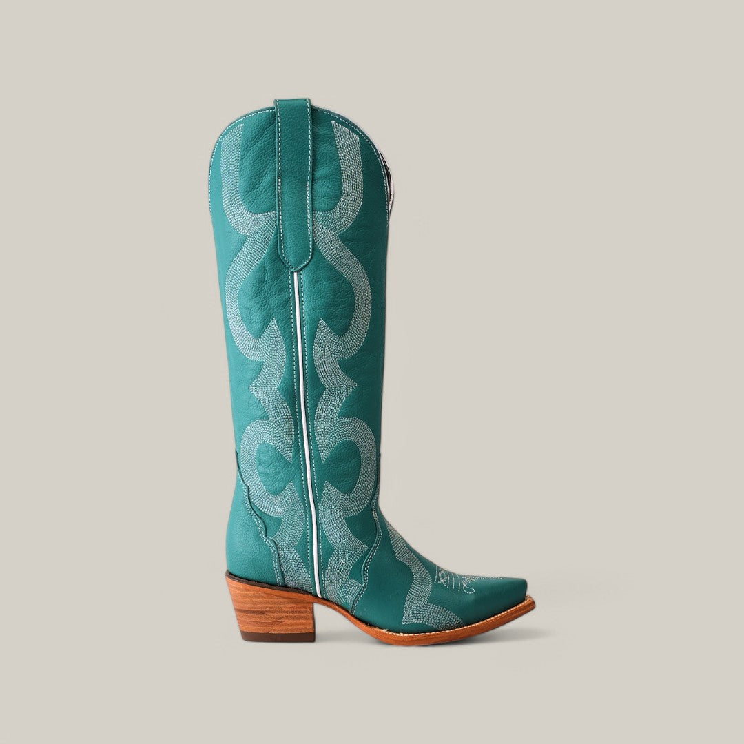 A single turquoise cowboy boot, made from premium materials, features light blue stitching on a plain backdrop. It has a wooden heel, pointed toe, and top pull straps. This striking piece echoes the elegance of Olimpia Green Teels Tall Shaft Snip Toe boots.