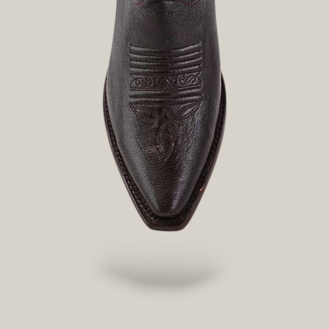 A close-up of the snip toe on the Rush - Brown boot, showing detailed stitching in dark brown leather, set against a plain beige background with a soft shadow beneath.