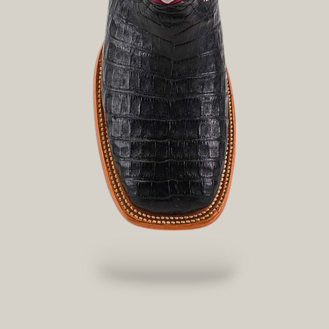 A close-up of the Exotic Caiman Horn Back - Black - Square Toe boot showcases its textured horn back design and brown stitched edging, set against a plain light gray background.