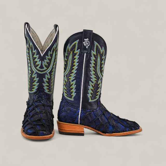 A pair of Exotic Pirarucu Fish - Navy Black - Square Toe boots with textured leather, green and yellow stitching, tan soles, and white piping, displayed against a plain light background from our Platinum Collection.