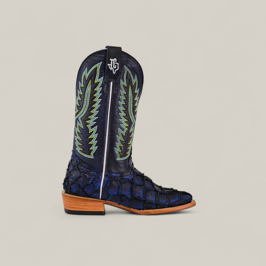 A single Exotic Pirarucu Fish - Navy Black - Square Toe boot, crafted from textured fish leather with light zigzag stitching, a wooden heel, and a black pull strap with a white logo. Set against a plain light background.