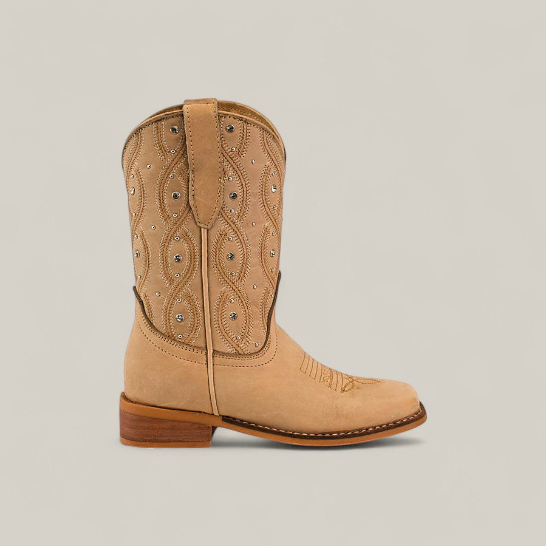 The Premiere Suede Bone - Square Toe Kids boots, in tan suede with decorative stitching, metal studs, pull straps, and a low wooden heel, are shown on a plain light background.