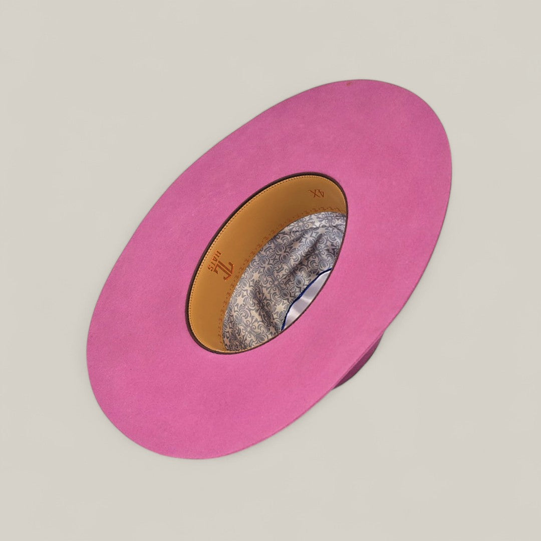 The 4x Pink - TC Hats is a wide-brimmed, bright pink Open Crown Texana Western hat displayed upside down, showcasing its tan patterned interior lining and decorative band against a plain light background.