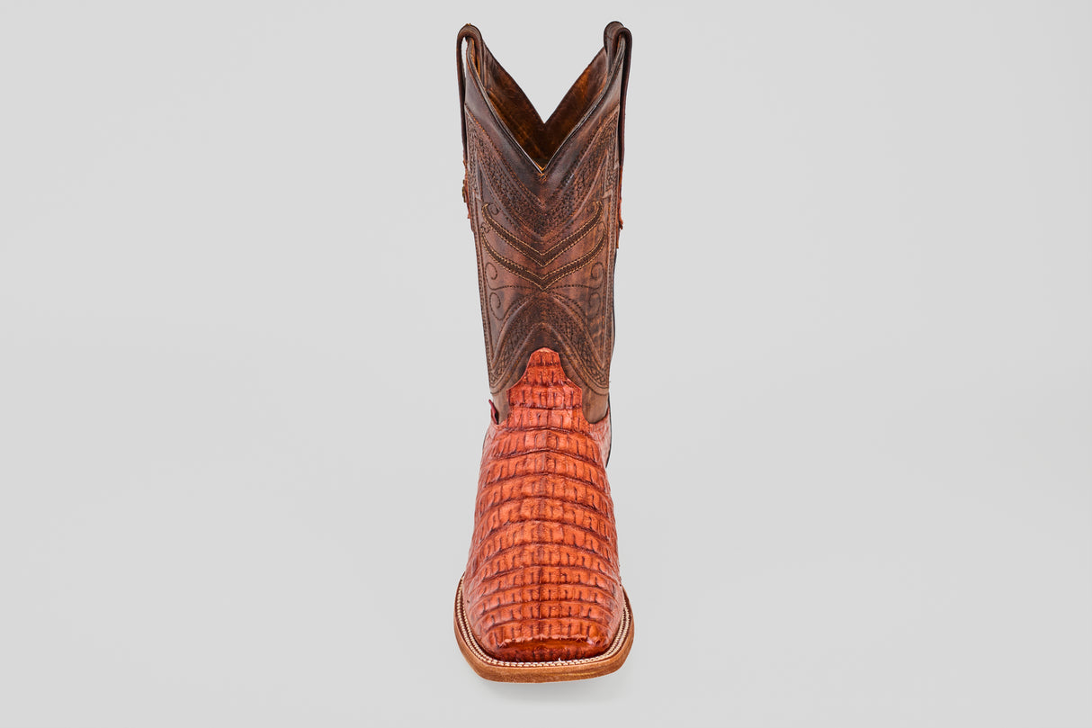 The Exotic Caiman Horn Back - Brandy - Square Toe boot, featuring a brown textured shaft and reddish patterned foot, is displayed facing forward on a plain light gray background.
