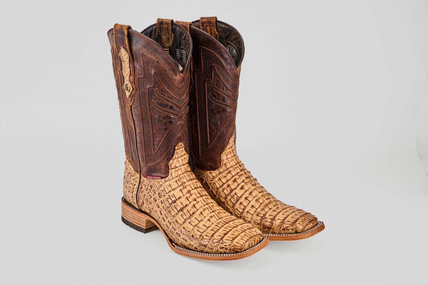 The Exotic Caiman Horn Back - Antique Square Toe boots feature tan, textured caiman leather on the foot and heel, with a dark brown shaft decorated with stitching, shown against a plain light background.