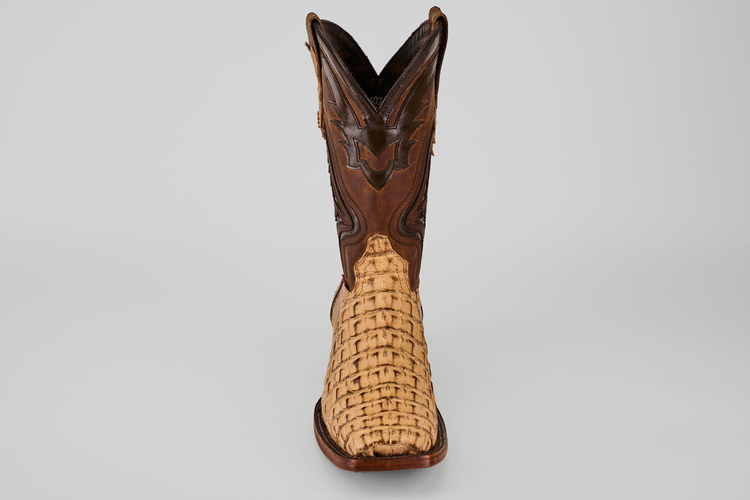 The Exotic Caiman Hornback - Antique - Rodeo Toe boot features a woven light tan lower, dark brown leather upper, and antique rodeo toe, displayed upright and facing forward on a plain light gray background.