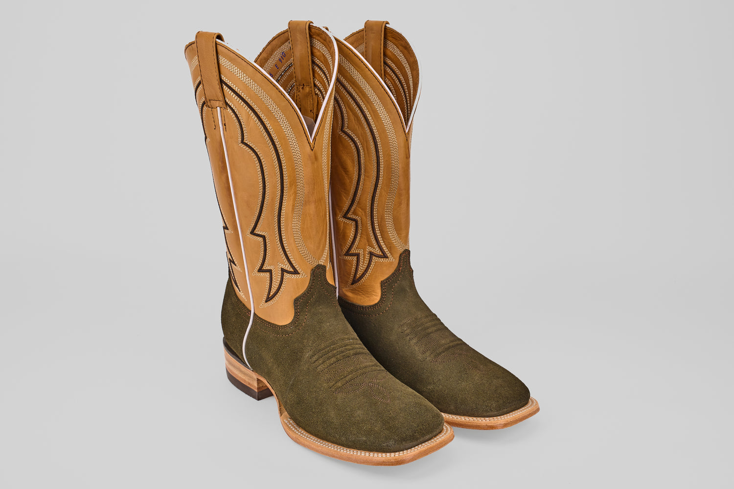 The Prime Suede Green Olive - Square Toe boots feature tan leather shafts, dark green olive suede lowers, decorative stitching, and a square toe design, displayed against a plain light background.