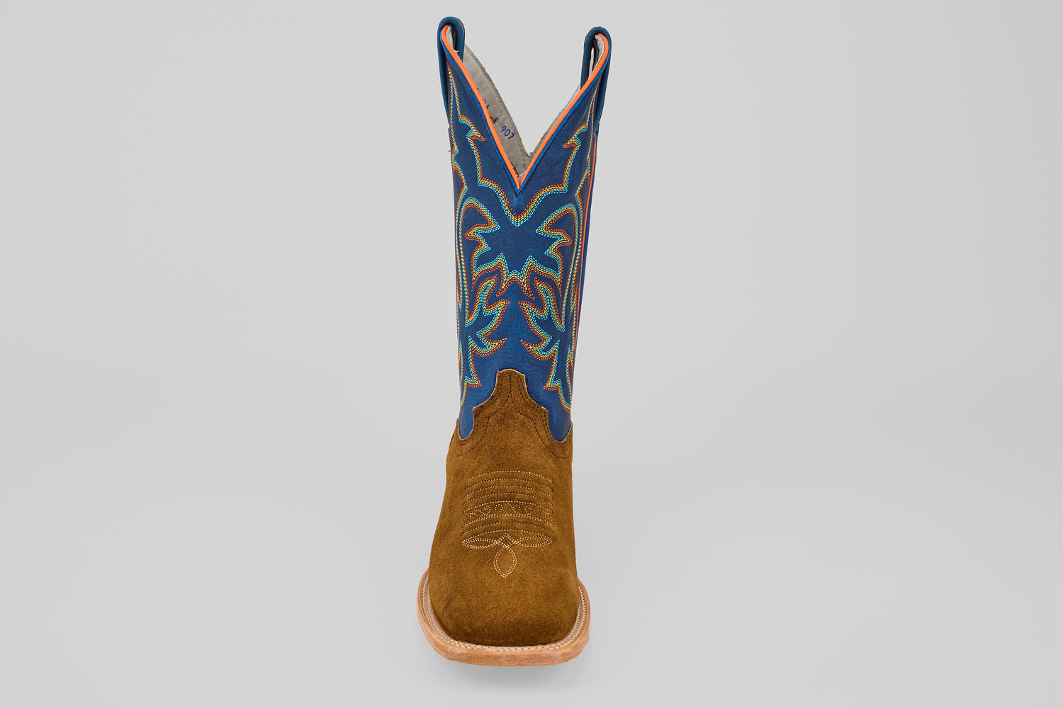 The Gold Suede - Square Toe boot features a brown suede foot and a tall blue shaft with multicolored decorative stitching, displayed upright and facing forward against a plain light background.
