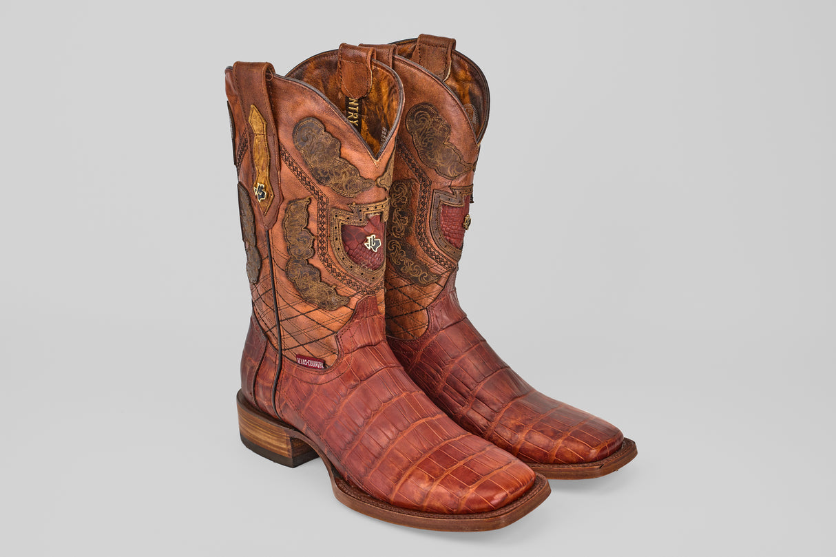 The Exotic Alligator Tail - Brick - Square Toe boots feature genuine reddish-brown alligator leather with intricate stitching and decorative shaft patterns, showcased against a plain light gray background.