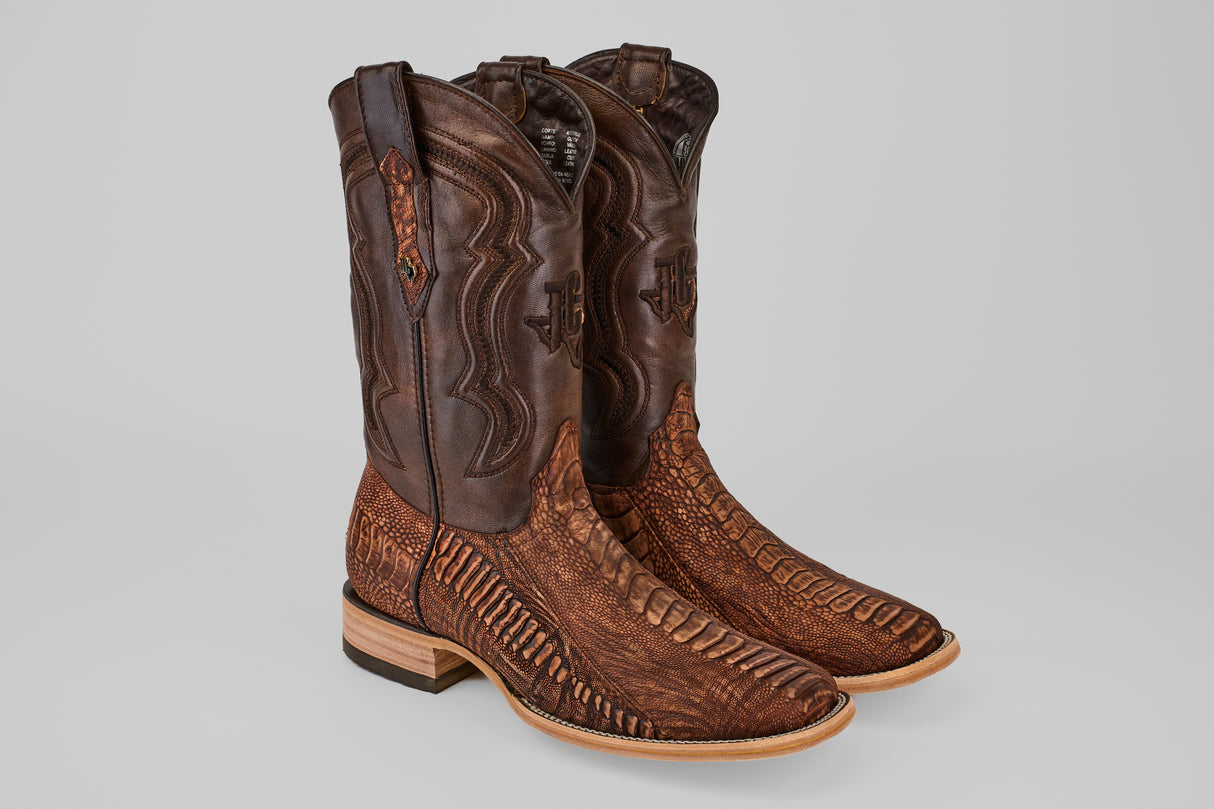 A pair of Exotic Full Quilt Ostrich Leg boots in Rustic Brick with square toes, decorative stitching, and textured patterns, featuring wooden heels, displayed on a plain gray background.