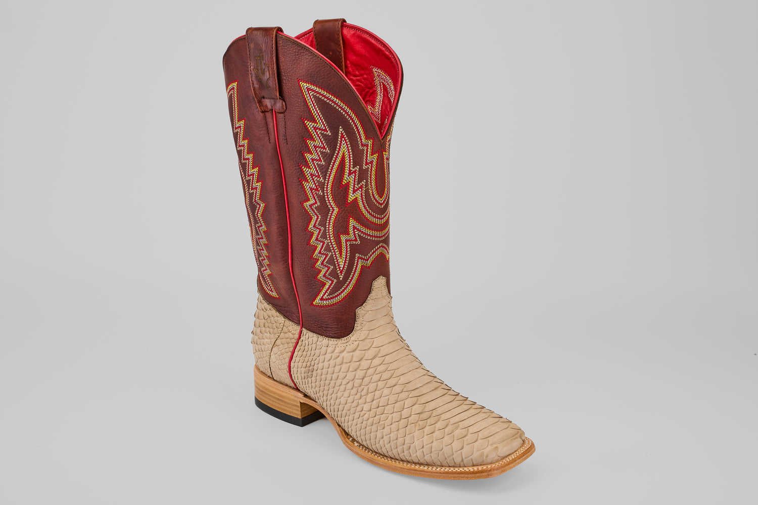 The Braxton - Cappucino - Square Toe is a luxury mens boot with a tan, python-textured lower half and tall, dark red shaft with yellow stitching and pull straps, finished with a wooden heel for timeless Western appeal.