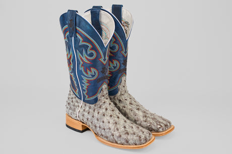 The Russell - Rustic Gray - Square Toe boots feature blue and red embroidered shafts, light gray ostrich leather foot, square toes, tan wooden heels, and white piping for a classic Western look.