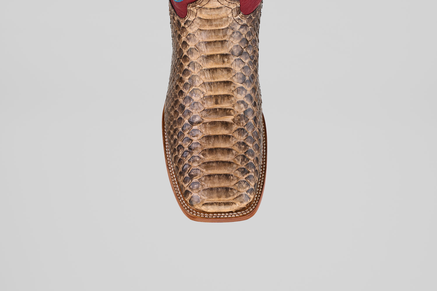 A close-up, top view of the Barlow - Taupe - Square Toe boot highlights its python leather texture, detailed scale patterns, and visible stitching—an eye-catching choice for mens statement footwear.