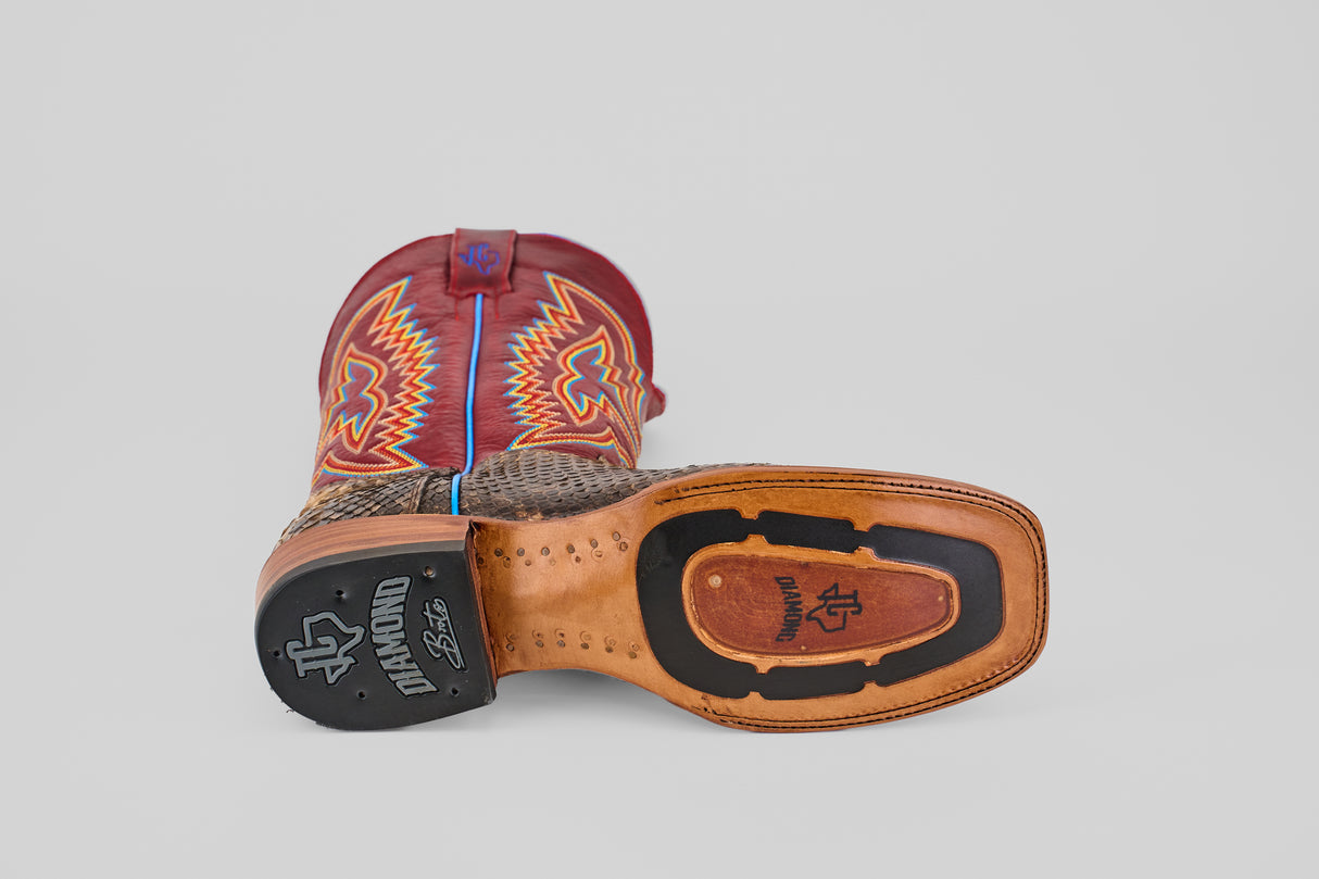 A single Barlow - Taupe - Square Toe boot lies on its side, displaying a textured brown sole with black and tan details and a bold red upper with vibrant stitching—making it a standout mens statement boot this season.