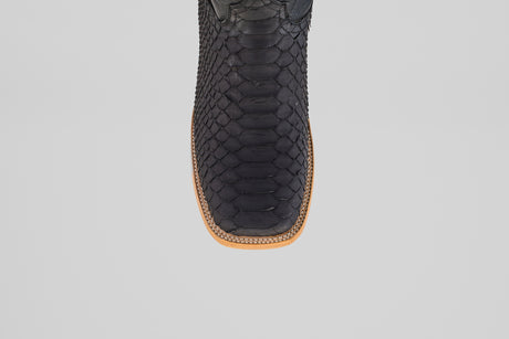 Close-up, top-down view of the toe area of the Wayne - Matte Black - Square Toe boot, featuring matte black snakeskin, a brown leather sole, and decorative edge stitching against a plain light background.