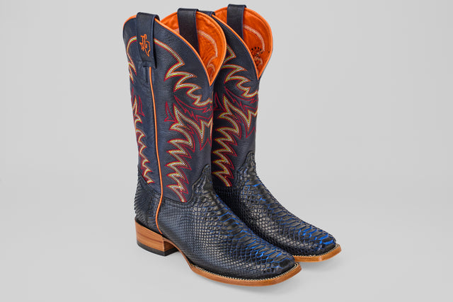A pair of McGraw - Navy - Square Toe boots, featuring a dark blue snakeskin pattern, light brown soles, wooden heels, orange interior lining, and colorful stitching on the shaft.