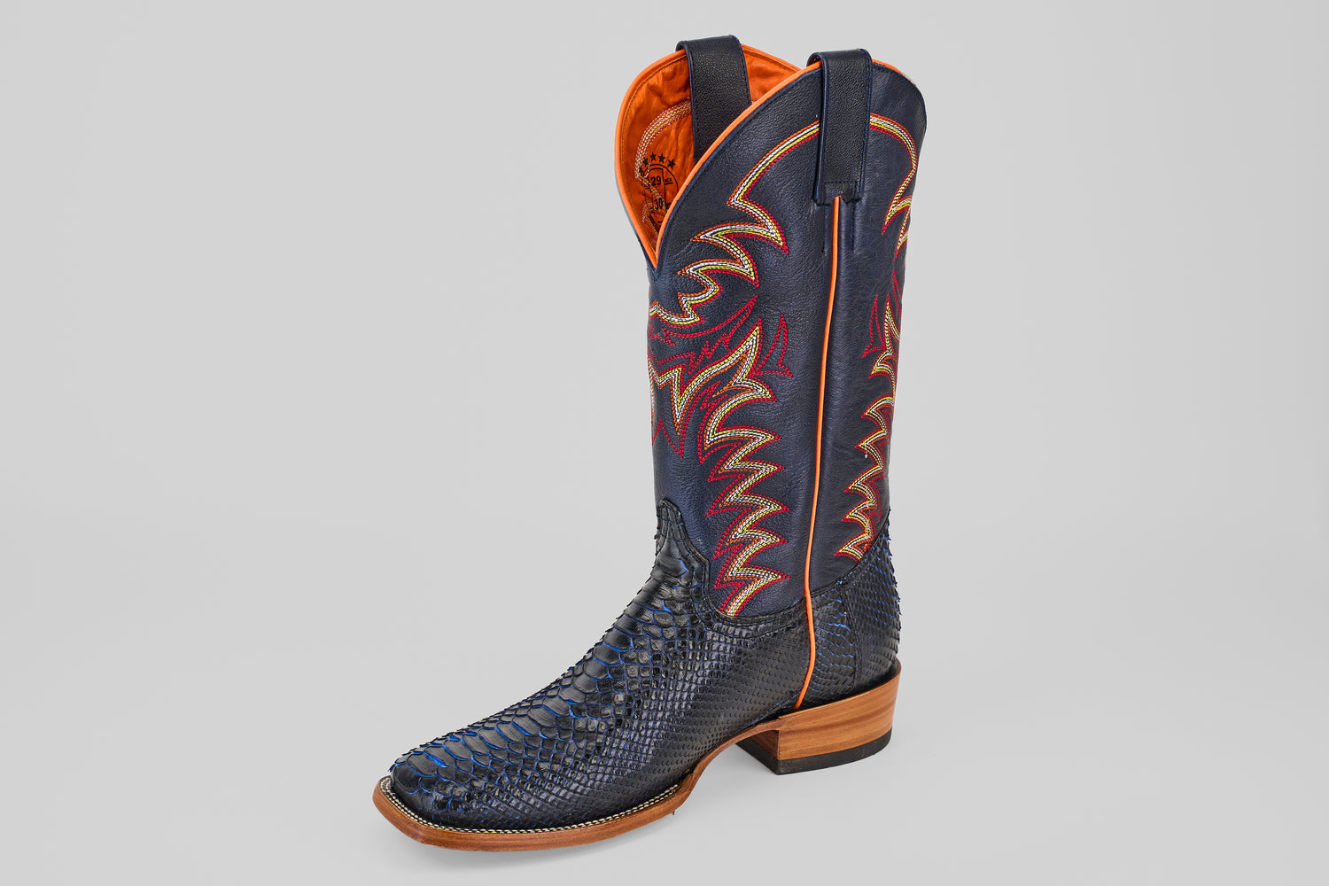 The McGraw - Navy - Square Toe boot from the Diamond Collection features orange and red stitching, a textured snakeskin lower, orange lining, and a light brown stacked heel.