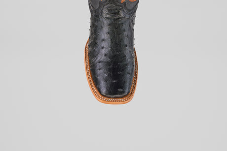 Top view of the Steele - Black - Square Toe cowboy boot in luxury ostrich leather, featuring a brown sole and white decorative stitching along the edge, set against a plain light gray background.