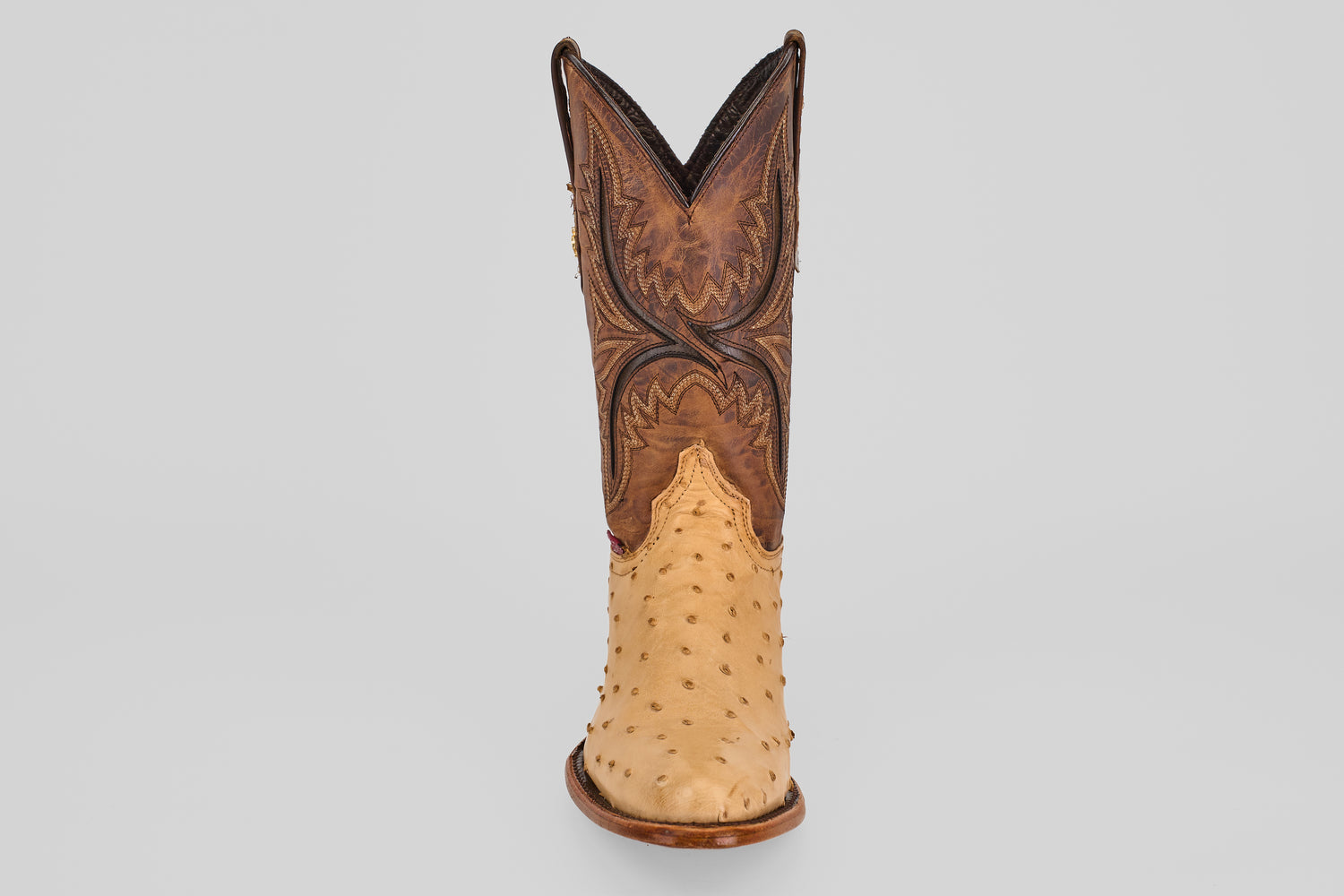 The Exotic Full Quilt Ostrich - Orix - Round Toe boot stands upright, featuring a tan quilted ostrich lower and a dark brown, ornately stitched upper, handcrafted in classic Western style on a plain light gray background.