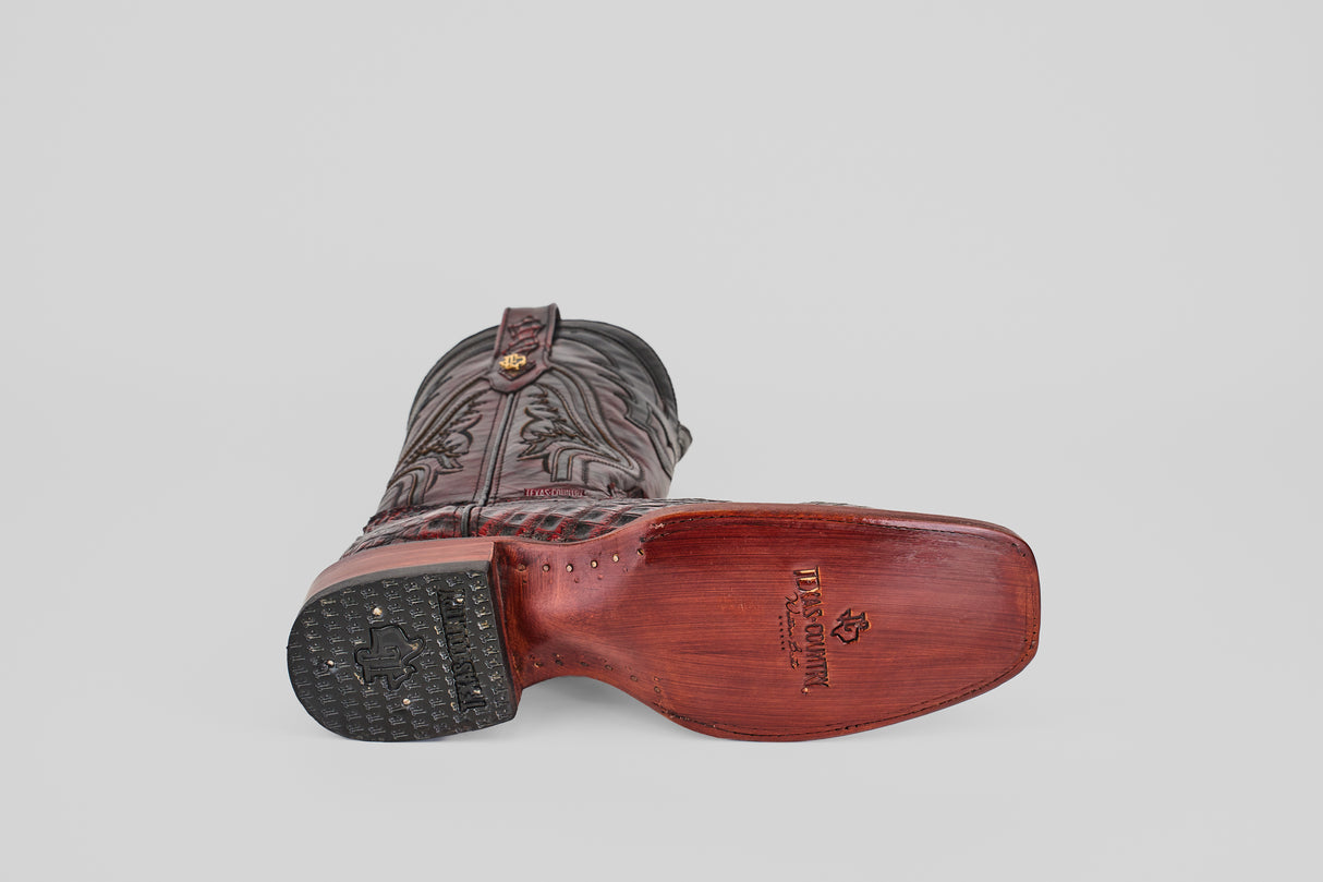 A single Exotic Caiman Hornback - Blackcherry - Rodeo Toe boot lies on its side with the LUCCHESE brand engraved on the sole, detailed stitching, a wooden heel, and a plain light gray background highlighting its design.
