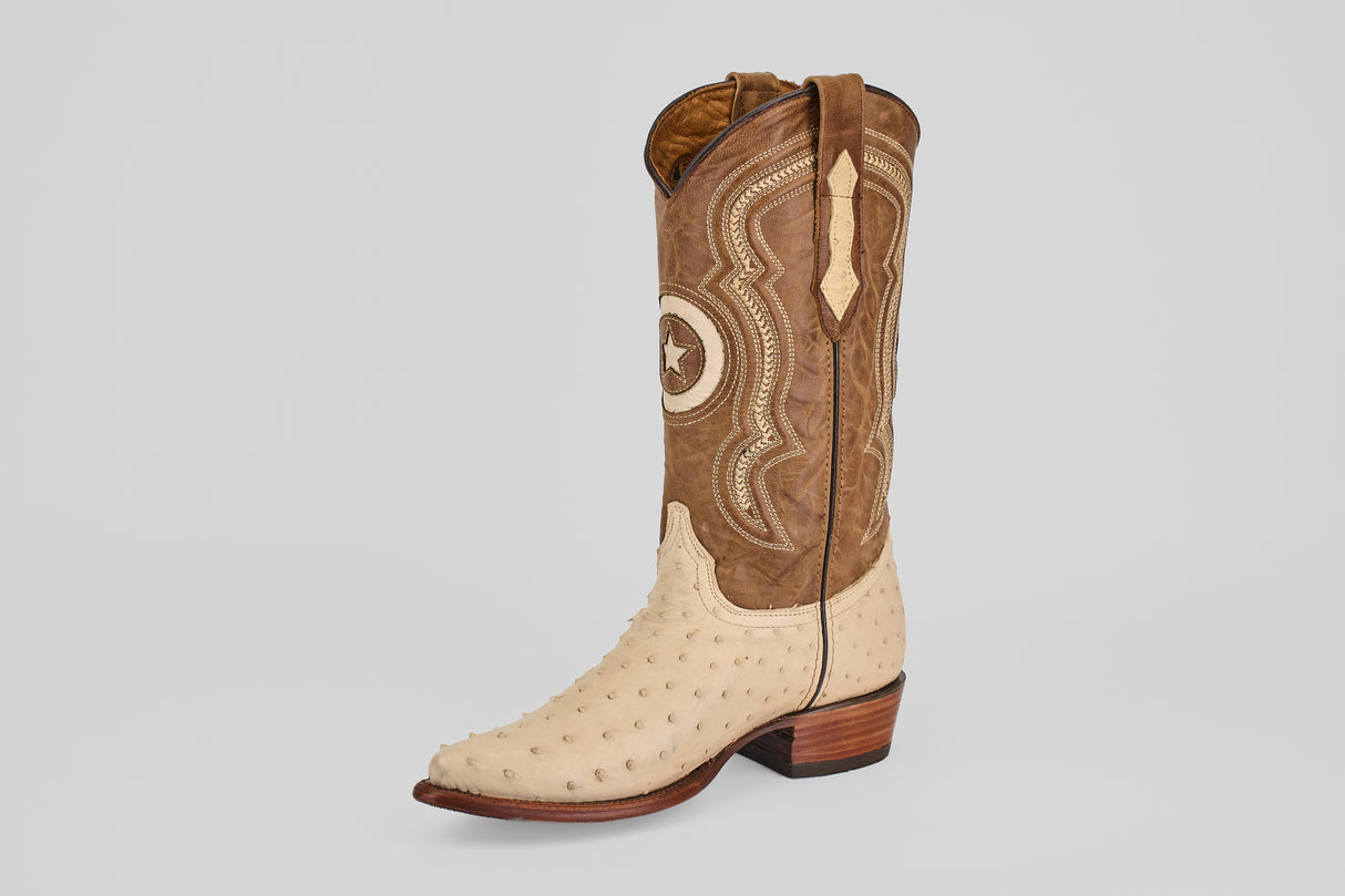 The Austin - Bone - Snip Toe showcases a single western boot with a tan shaft, decorative stitching, and a light textured ostrich leather foot, set upright on a plain light gray background. A stylish choice for ostrich leather cowboy boot lovers.