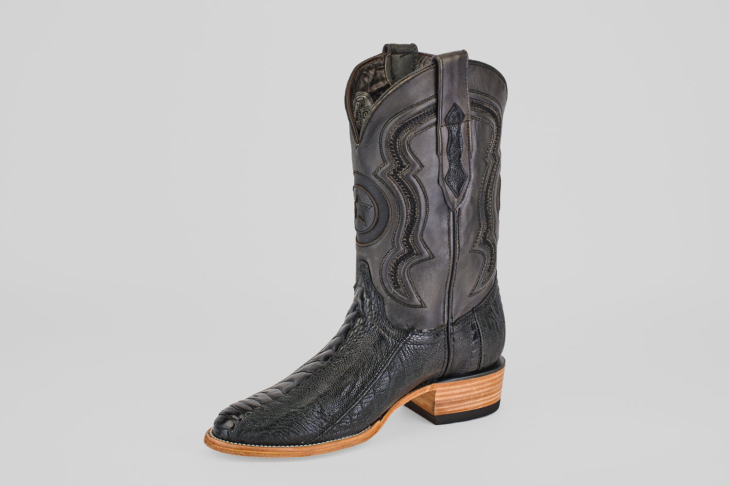 The Austin Leg - Black - Roper Toe is a single black western boot with decorative shaft stitching, a textured leather foot, and a light brown wooden heel and sole, set against a plain white background.