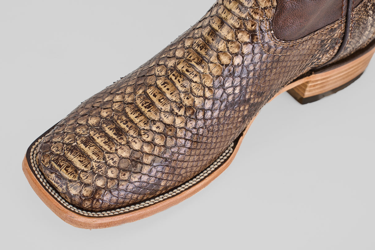 Close-up of the Tanner – Dune – Square Toe boot, crafted from brown python leather with detailed stitching, highlighting its western-inspired design against a light gray background.