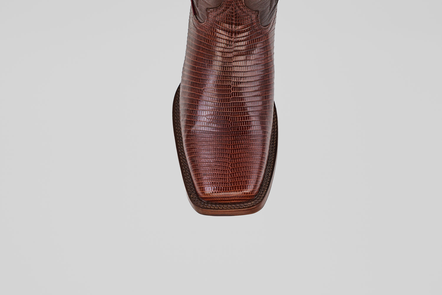 The Blaze – Brown – Rodeo Toe cowboy boot, made from genuine lizard leather with a textured finish and square toe, is shown from above against a plain light gray background, highlighting its refined western style.
