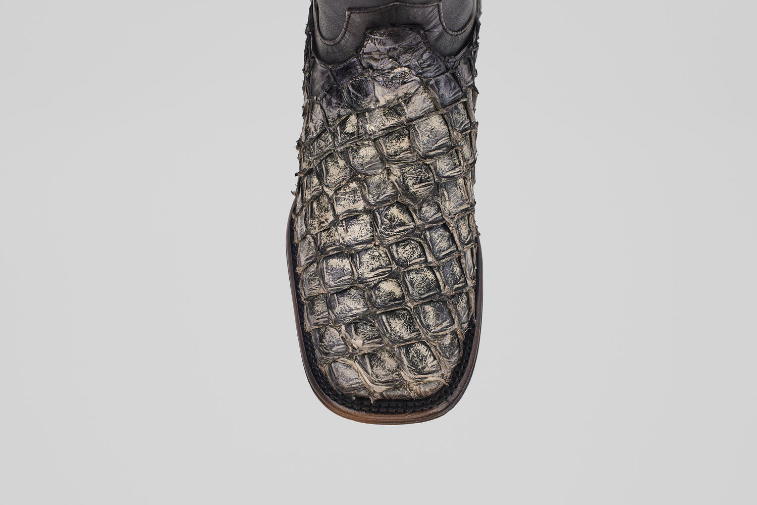 A close-up of the Conor Platinum - Newspaper - Square Toe (Diamond) cowboy boot, featuring dark, textured crocodile-patterned leather and a brown edge, displayed against a plain white background.