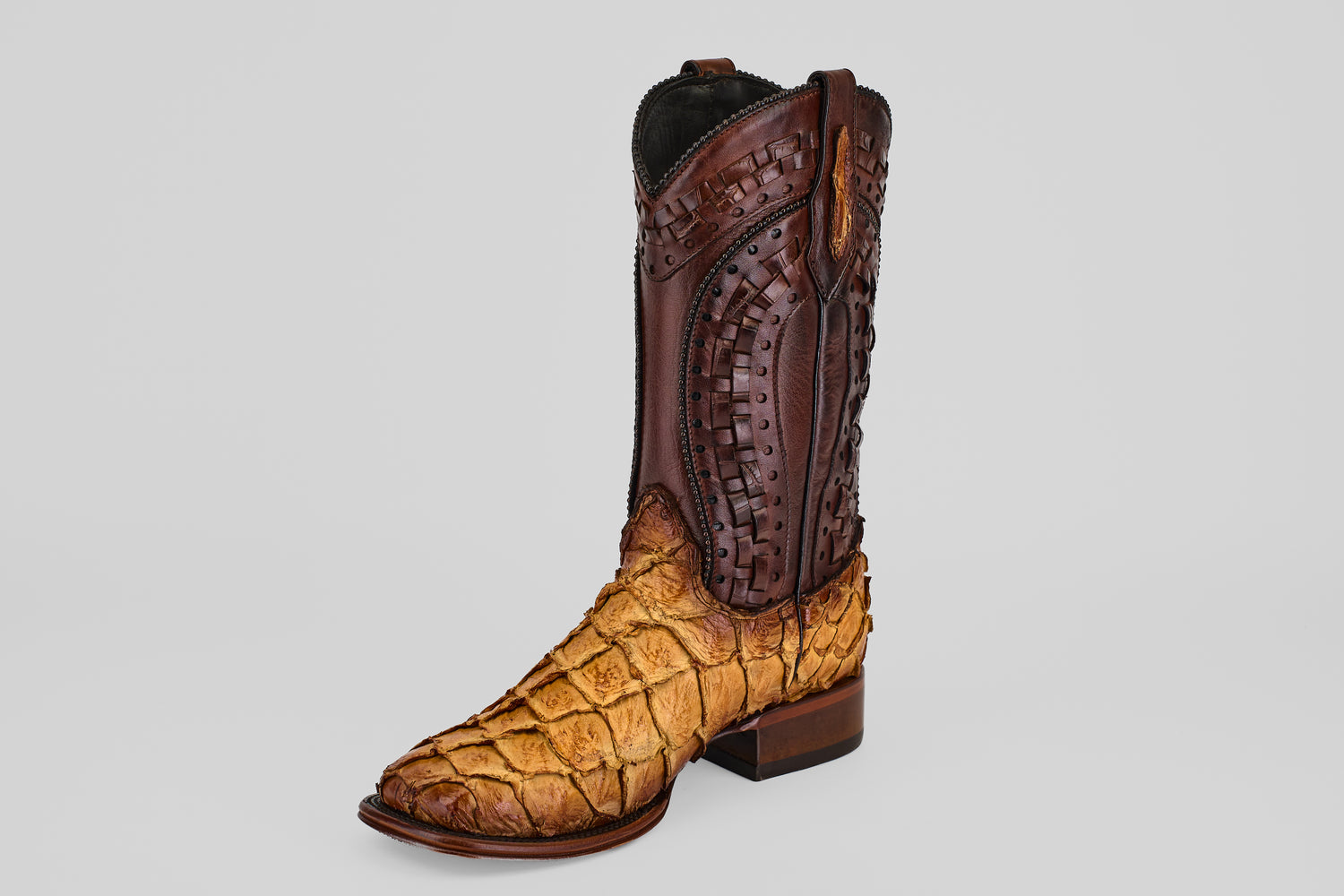 The Conor Platinum - Buttercup - Square Toe (Herradura) is a men’s western boot with a tan textured reptile skin foot and tall dark brown stitched leather upper, showcased against a light gray background.
