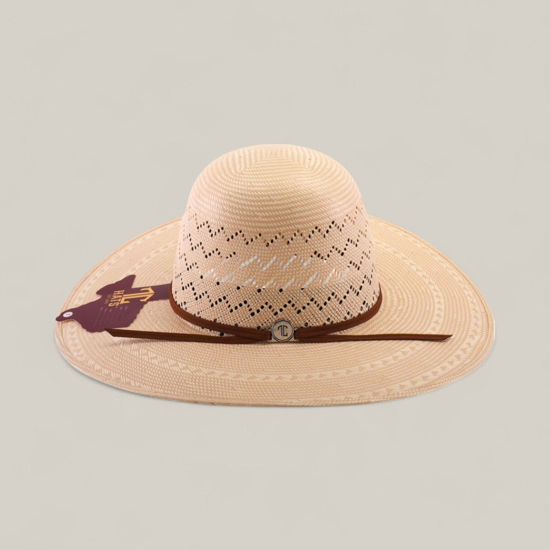The 30X Zig Zag - Open Crown is a wide-brimmed, light tan straw hat with decorative cut-out patterns, brown hatband, round metal emblem at the front, and maroon side tag. Ideal for unique style seekers. Shown on a plain background.