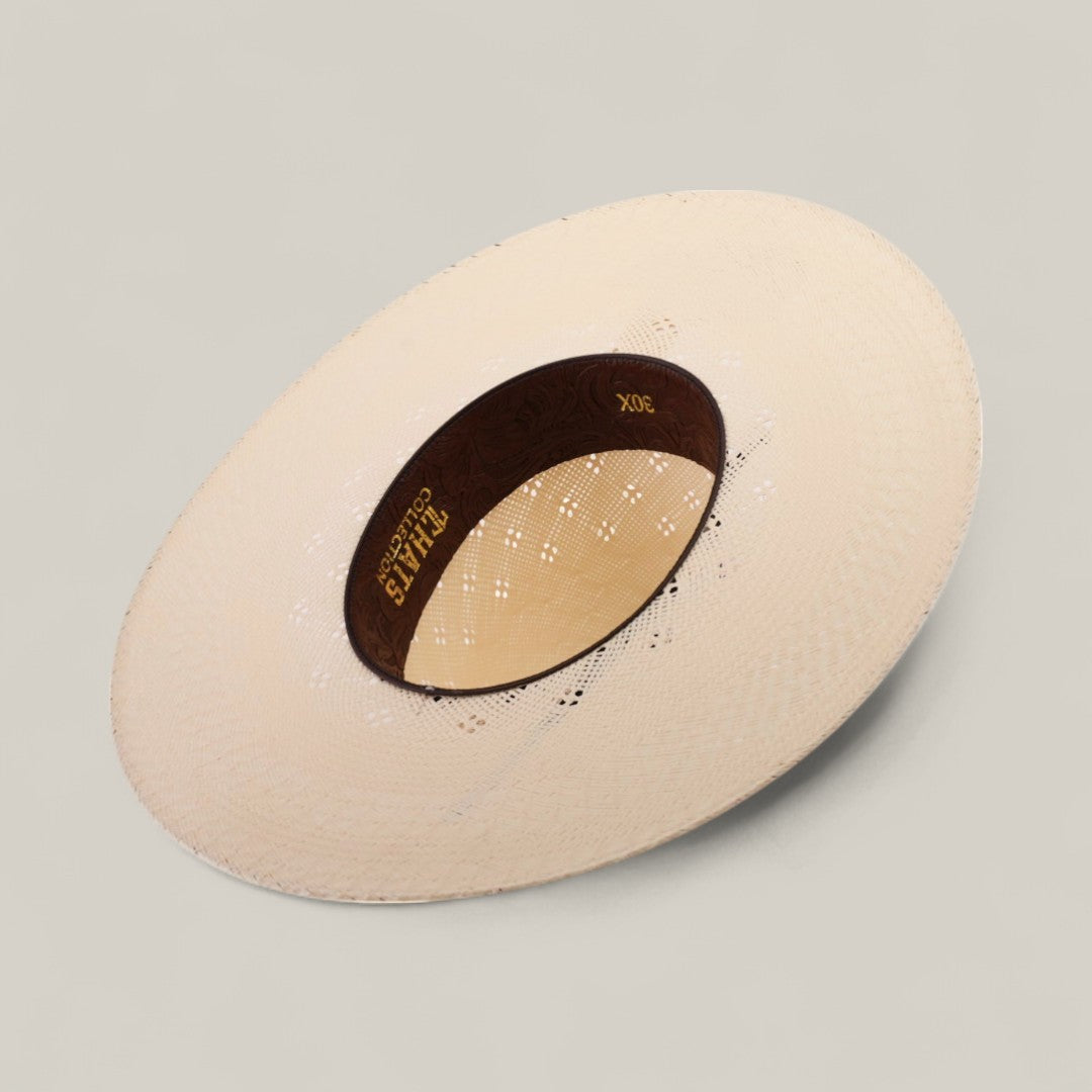 The 30X Clover - Open Crown hat, made of light-colored woven straw, is pictured upside down on a neutral background, showing its wide brim and a brown inner band with gold 30X Clover text.