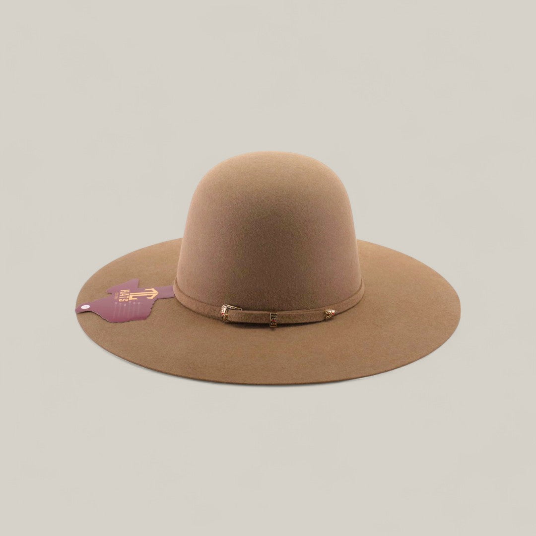The 10x - Natural - TC Hats is a wide-brimmed, light brown felt western hat with a simple band around the crown, featuring a purple tag on the left brim. The hat is displayed against a plain beige background.