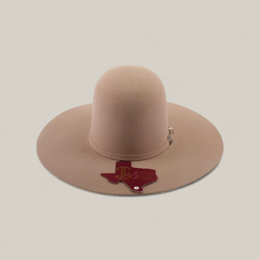A 4x - Natural - TC Hats, a light brown, wide-brimmed felt Western hat with a decorative crown band, is shown on a plain background. A Texas-shaped tag reading TX HAT hangs from the brim.