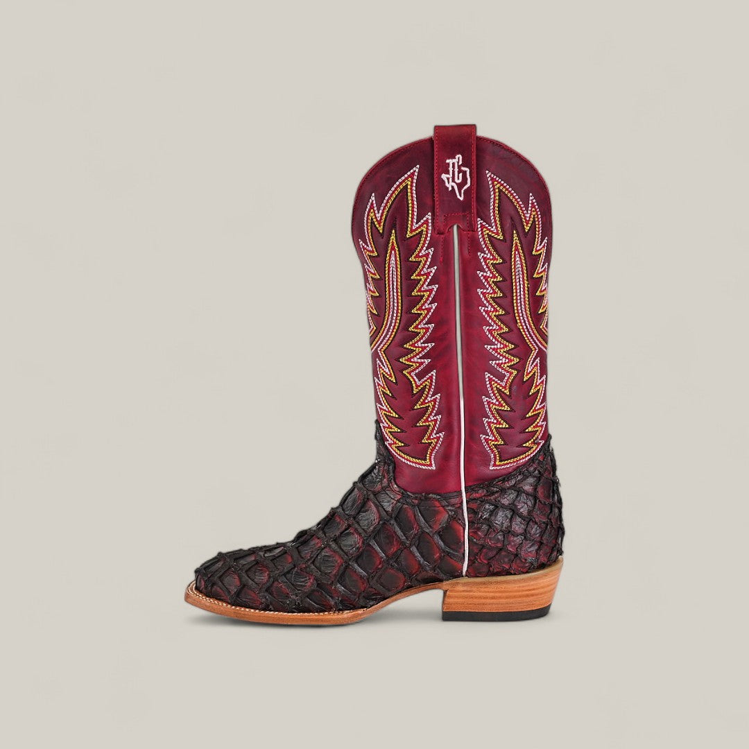 The Maverick - Wild Cherry - Square Toe boot features a black textured lower, red upper shaft with yellow and white embroidery, wooden sole, small logo near the top, and is displayed on a plain light background.