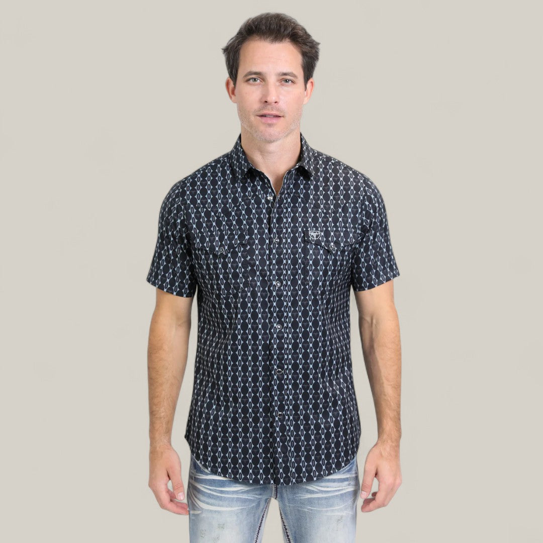 A man with short dark hair wears the Mens Performance Western Short Sleeve Aztec Print Navy Shirt (PGW10646) and light blue jeans, standing facing forward against a plain light beige background.