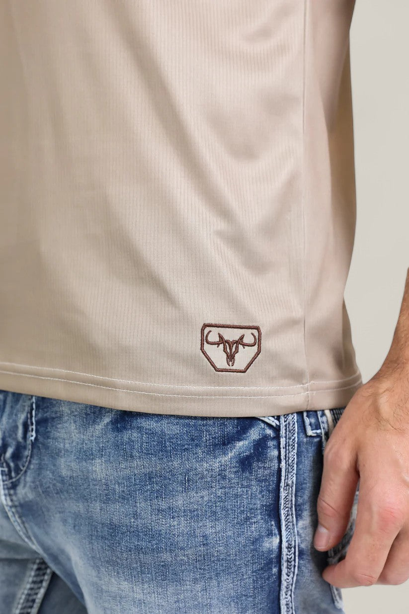 A person wearing light blue jeans and the Men’s Performance Fabric Aztec Panoramic Print Khaki Polo (PGP10607); only their torso and one arm are visible.