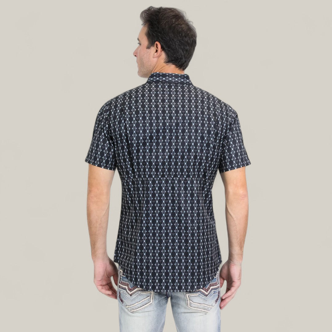 A man is standing with his back to the camera, wearing the Mens Performance Western Short Sleeve Aztec Print Navy Shirt (PGW10646) and light blue jeans against a plain light gray background.