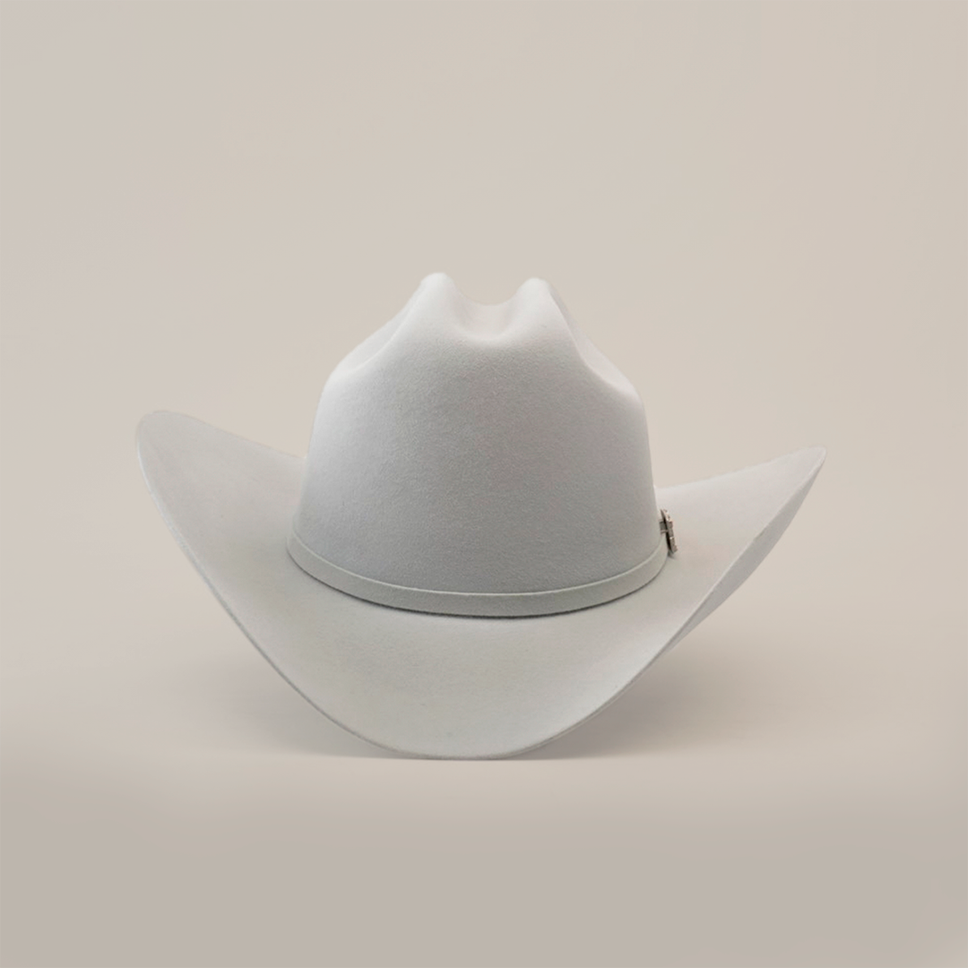 The 100X Independencia Platinum cowboy hat, in light gray, captures the El Presidente style with its wide brim and slightly curved crown, elegantly resting on a smooth surface.