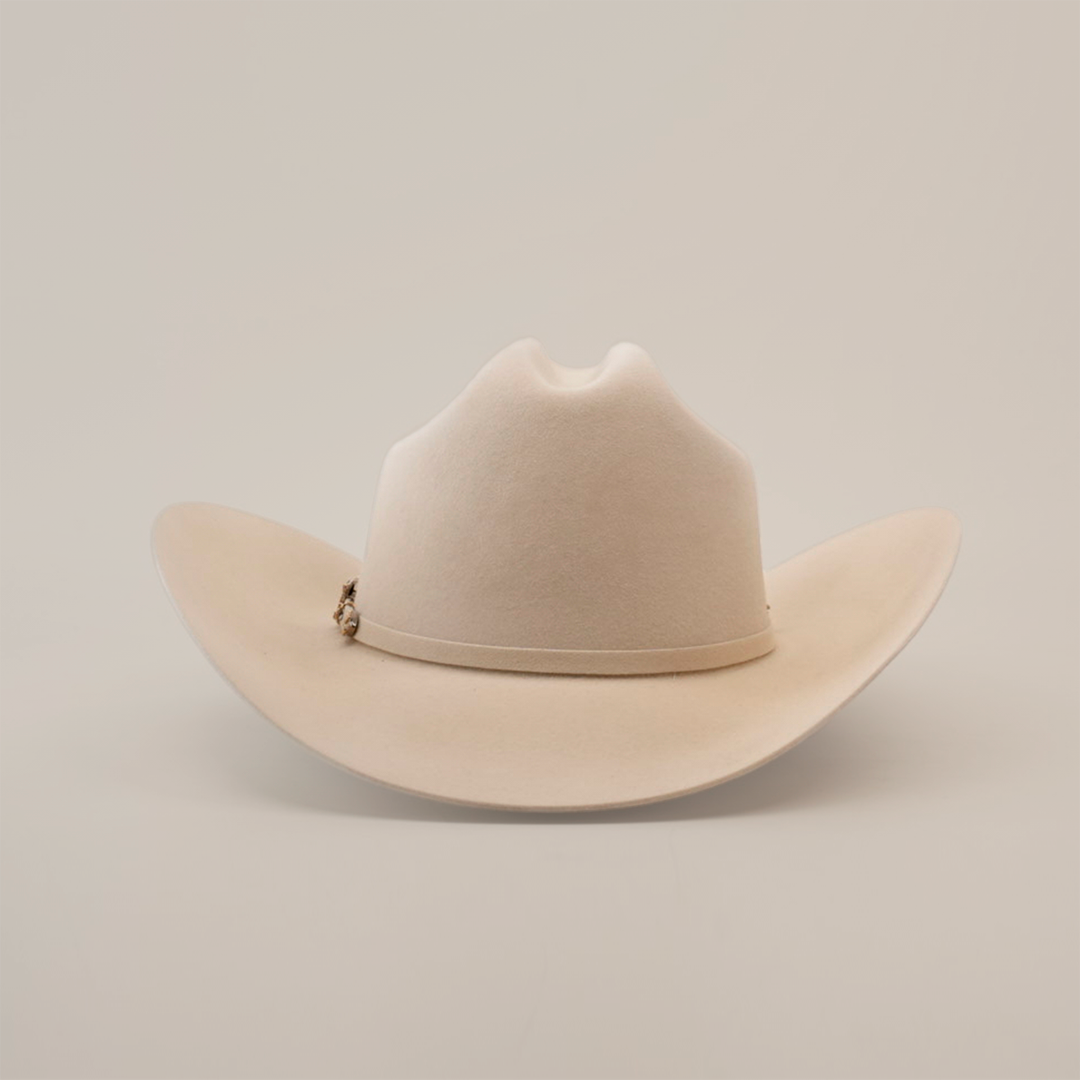 The Larry Mahan 100X Independencia Belly is a beige cowboy hat with a wide brim, dented crown, and a subtle decorative band. Crafted from premium full beaver fur, this luxury western headwear rests on a plain white background.