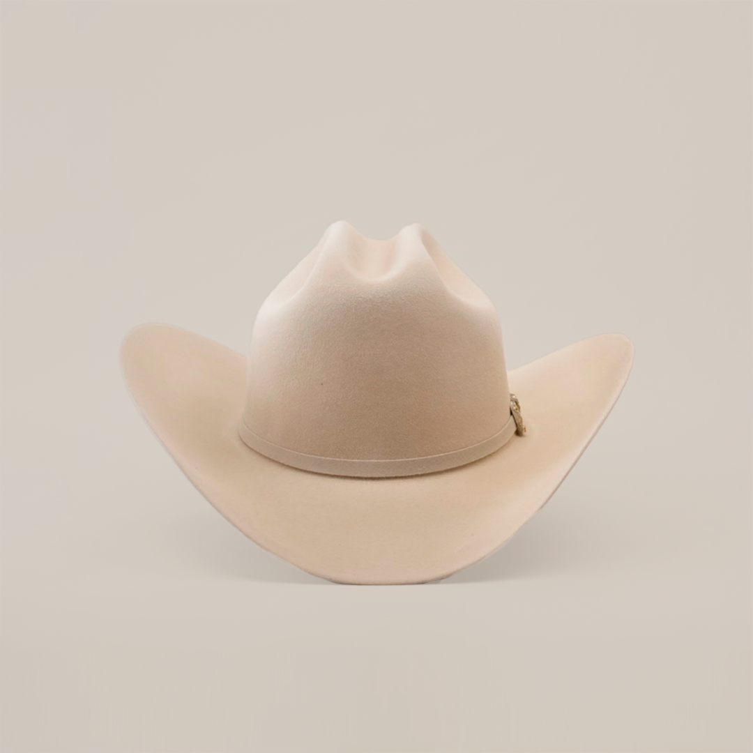 The 10X Jerarca Belly is a beige fur felt cowboy hat with a wide brim and creased crown, embodying classic western style, set against a plain white background.