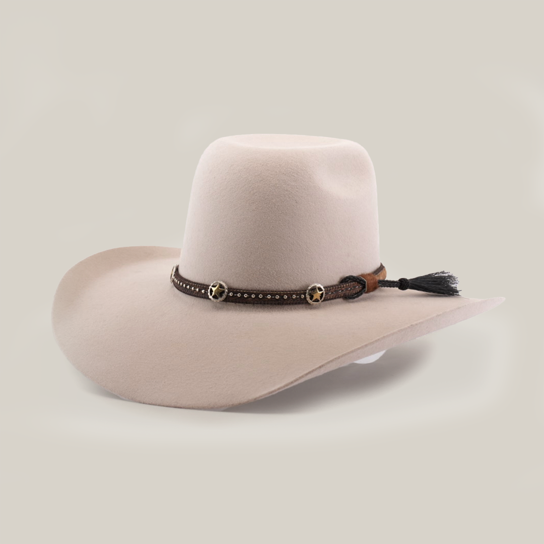 The 6X Brazil Belly is a wide-brimmed beige cowboy hat made from genuine sheep wool, featuring a black premium leather band with small stars and a brown tassel. It has a rounded crown and slightly curved brim edges.