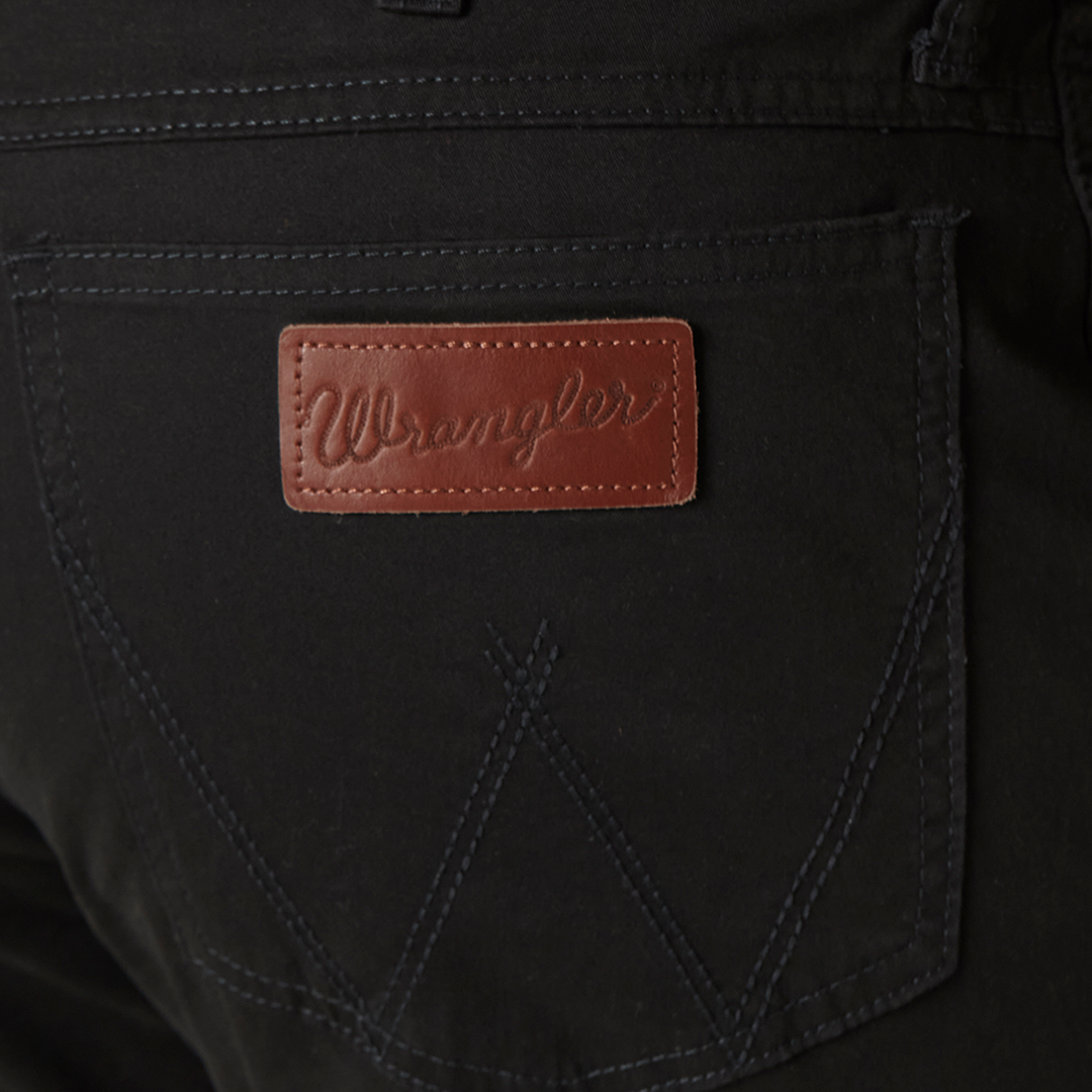 Close-up of Mens Wrangler Retro Slim Fit Straight Leg Pant - 88MWZBK in black, highlighting the back pocket with dark stitching and a brown leather patch embossed with Wrangler, showcasing their premium denim craftsmanship.