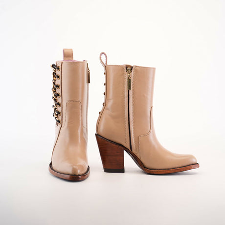 A pair of tan leather boots with medium heels. One boot shows a side zipper, while the other reveals decorative lacing on the side, both resting on a neutral background.