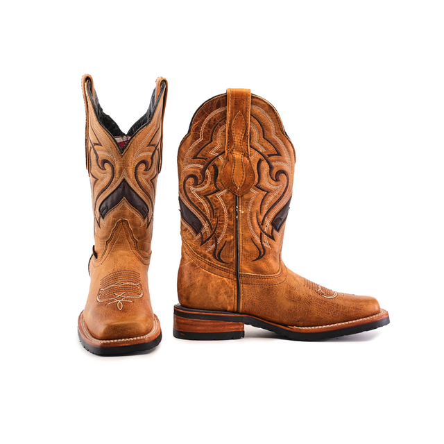 The Wild Mustard Slip Resistant Sole Rodeo Toe boots are a pair of brown cowboy boots made from cowhide leather, featuring intricate black and tan stitching on the shaft and a rodeo toe. One boot stands upright while the other is tilted to highlight their elegance, leather finish, stacked heel, and slip-resistant sole.