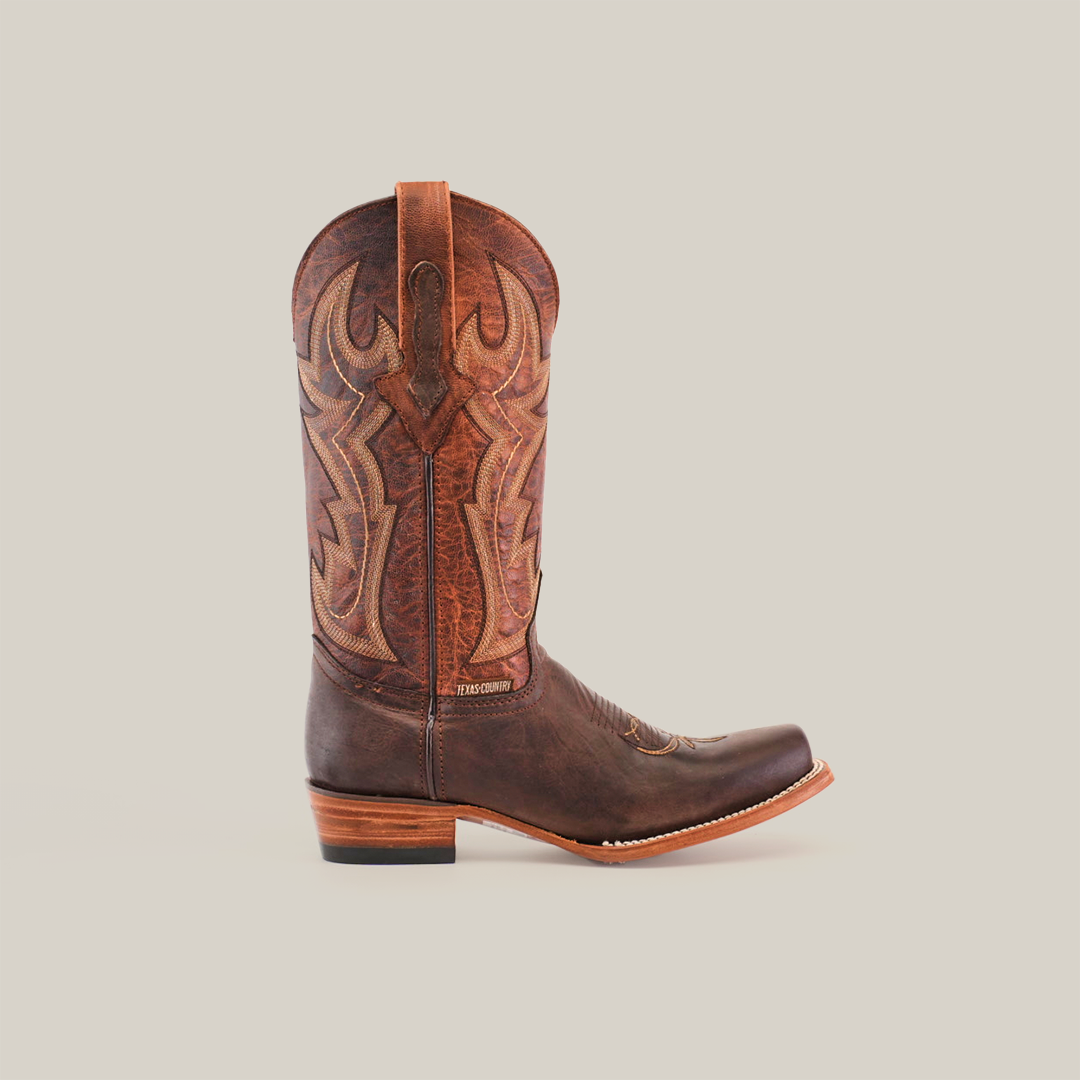 The Fresno Chocolate cowboy boot features a Wide Cutter Toe design, crafted from premium cowhide with intricate patterns and embroidery on the shaft, complemented by a wooden heel. Its elegantly displayed against a plain white background.