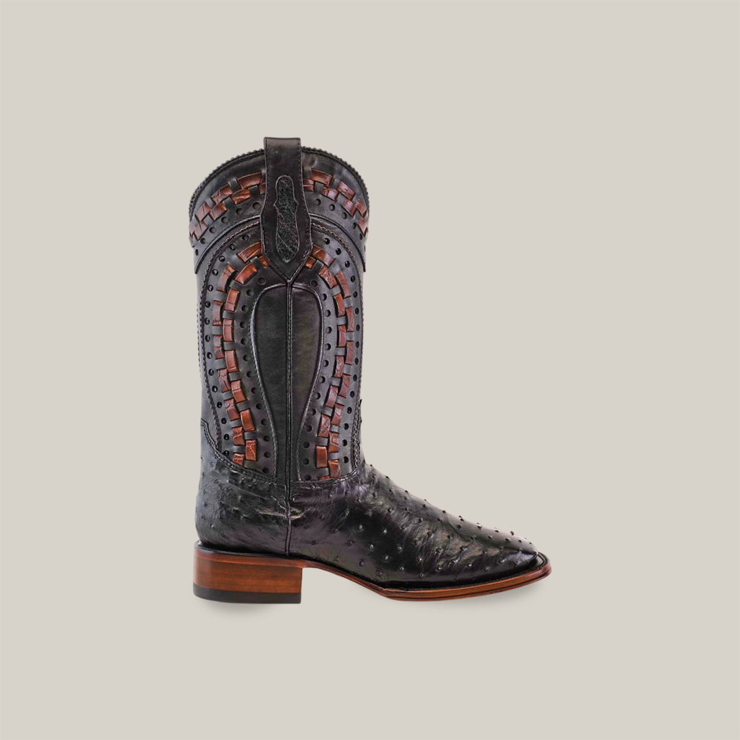 The Exotic Karoo Ostrich - Herradura boot in black, with decorative brown stitching and patterned inlays, showcases Western fashion. Made from premium ostrich leather, it features a square toe, slightly raised heel, and pull straps. Part of the Platinum Collection, its set against a plain light gray backdrop.