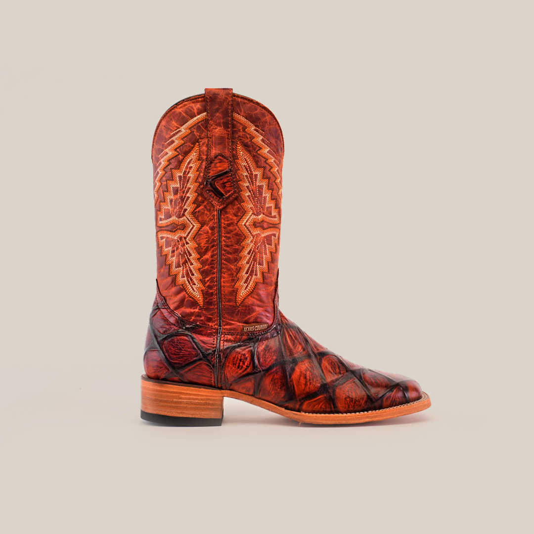 The Big Bass Pirarucu Print Cogñac - Square Toe cowboy boot, crafted from premium cowhide with intricate stitching in brown tones, features a low wooden heel and pointed toe, set against a plain white background.