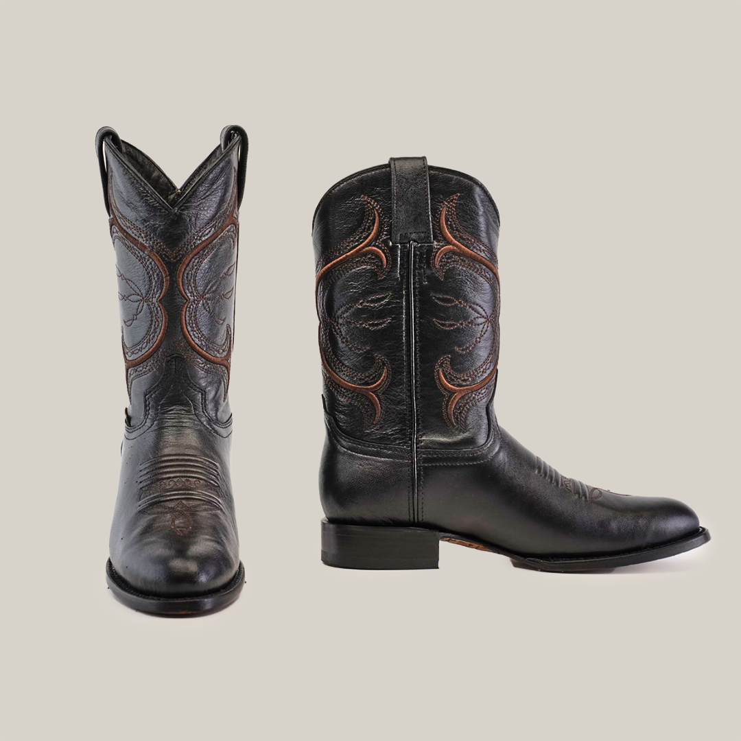 A pair of Rush Black - Roper Toe boots in premium cowhide leather, showcasing red stitching and a swirl pattern. One boot is forward-facing to highlight the toe, while the other is side-on to display pull straps, all against a plain white background that enhances their Western spirit.